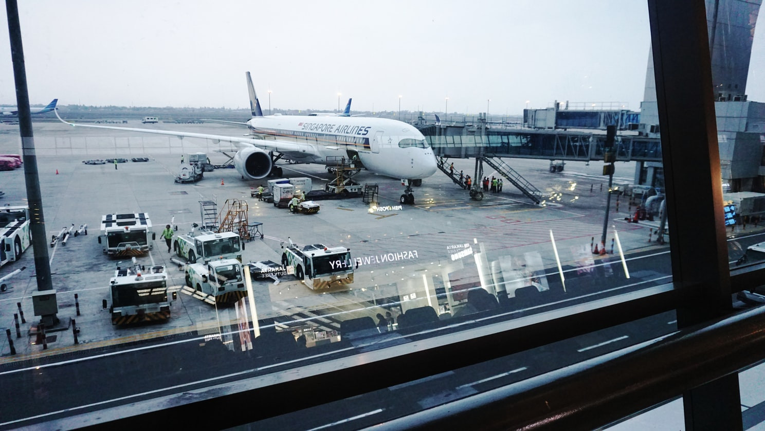 A plane on the ground in the airport with ground support vehicles nearby.