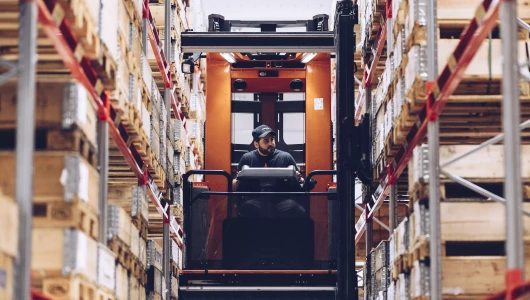 Forklift driver at warehouse shelves