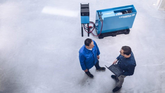 Two employees stand next to it and chargers and a battery system