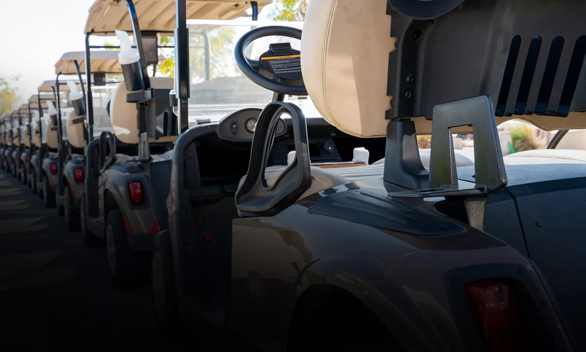 Several beige and black battery-powered utility vehicles lined up