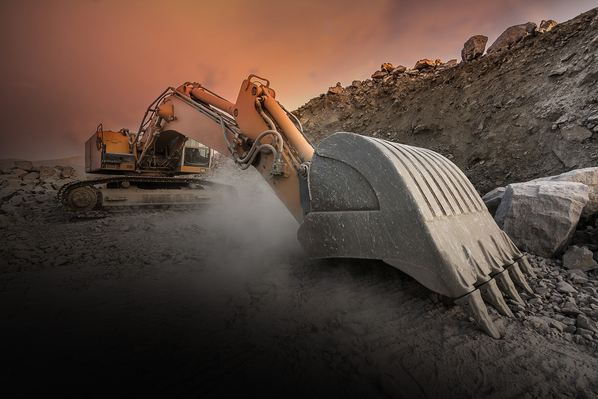 An orange electric excavator is working a hard and rocky ground, with a red sky as a back fond.