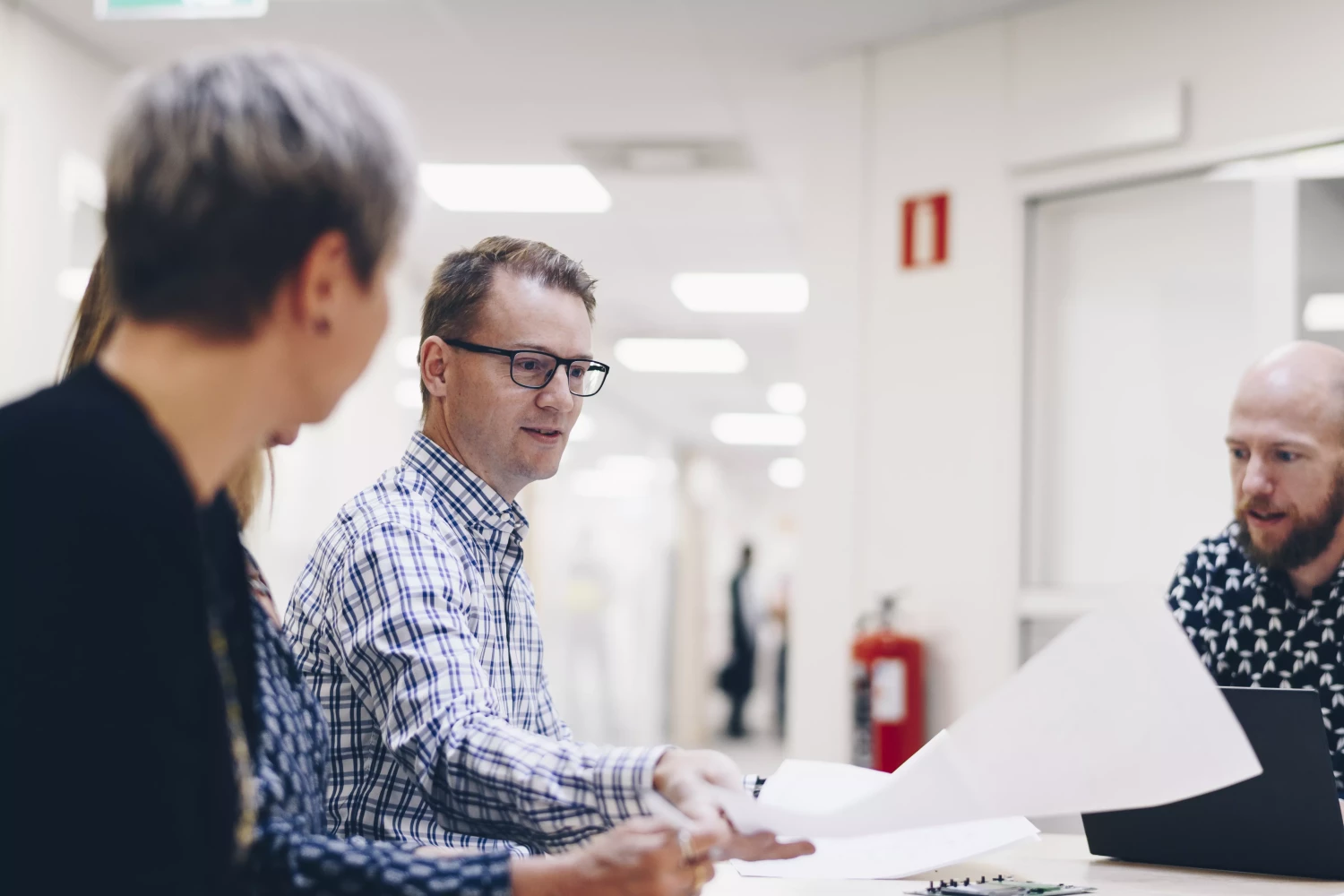 Three engineers at Micropower Group are looking at papers, discussing something in a meeting.