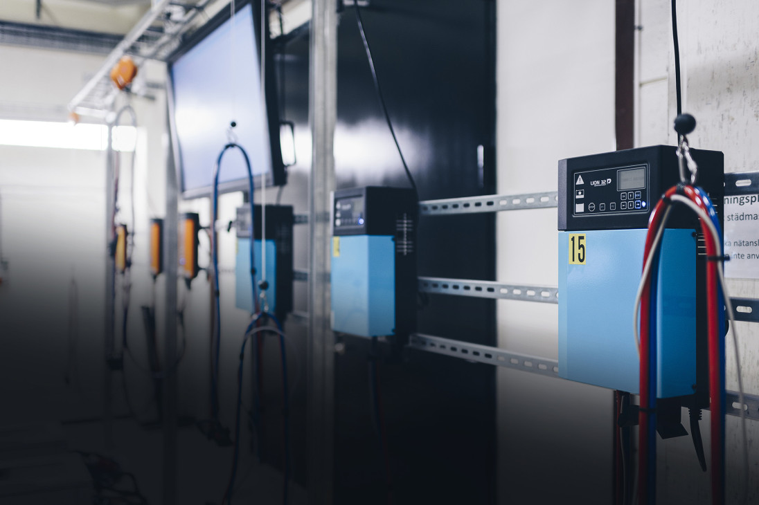 Three industrial battery chargers are hanging on a wall inside a building.