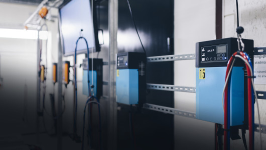 Three industrial battery chargers are hanging on a wall inside a building.