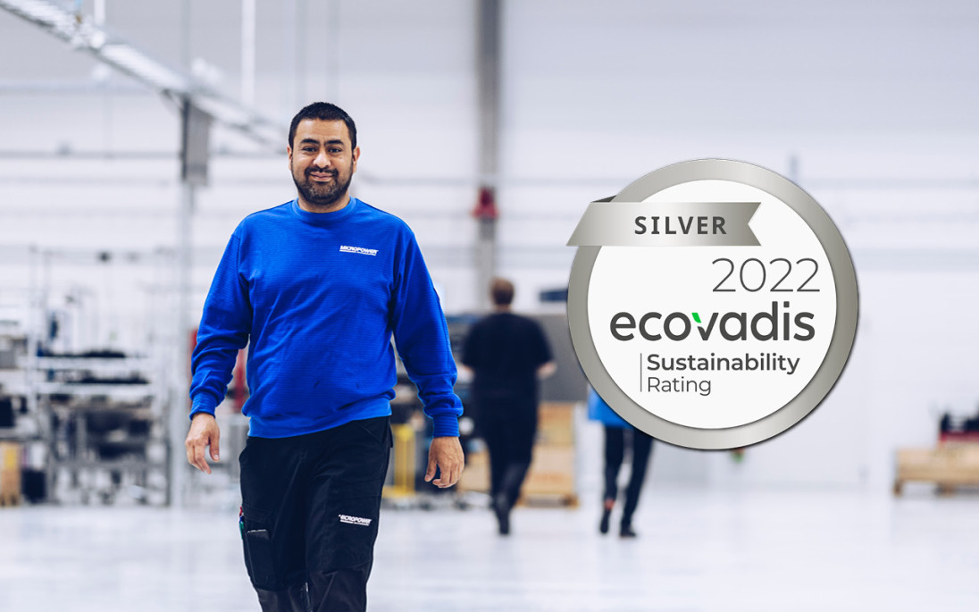 Happy employee in Micropower's battery factory with Ecovadis logo