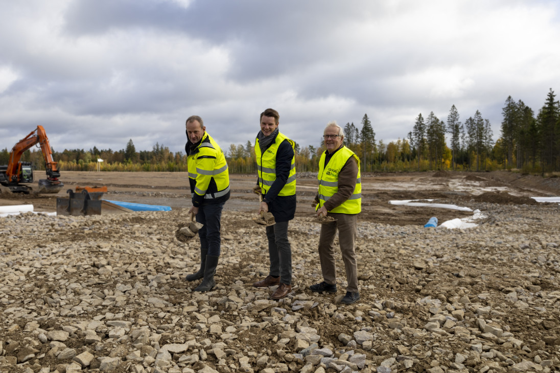 Three men with yellow vests and shovels take a first sod